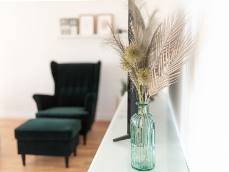 Grüner Sessel mit Hocker und Vase als Akzent im Apartment in Neuwied